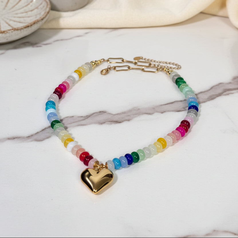 Necklace with colorful beads and a gold heart pendant on a white background