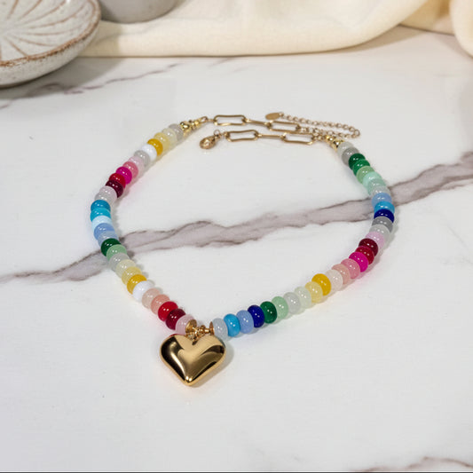 Necklace with colorful beads and a gold heart pendant on a white background