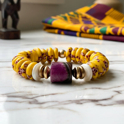 Yellow beaded bracelet with purple and gold accents on a white background