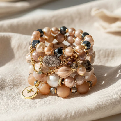 Stack of beaded bracelets with gold accents on a beige fabric background