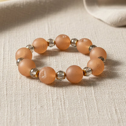Beaded bracelet with peach-colored beads on a beige fabric background