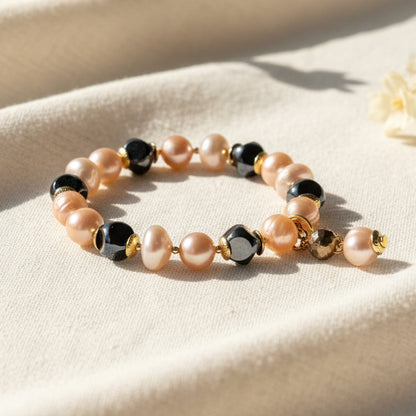 Beaded bracelet with peach, black, and gold beads on a linen background