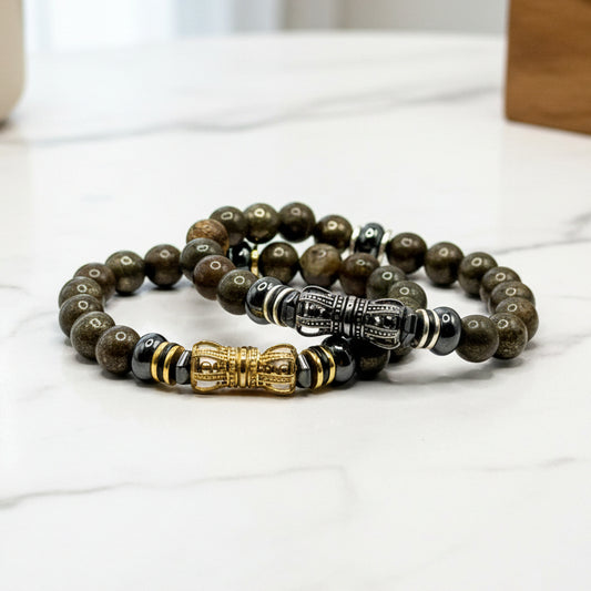 Two men's beaded pyrite bracelets with decorative elements on a white surface