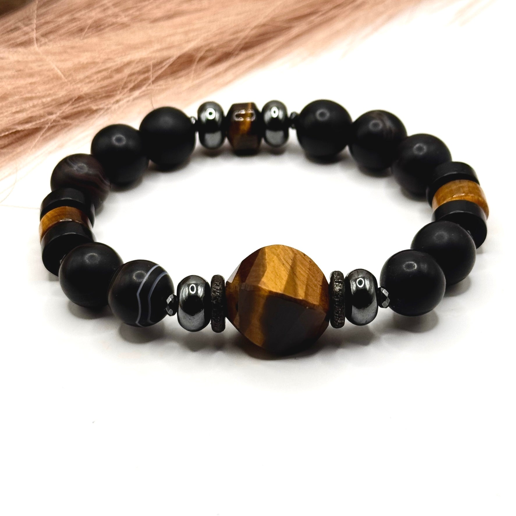 Black striped Agate beaded men's bracelet with Tiger Eye centerpiece on a white background