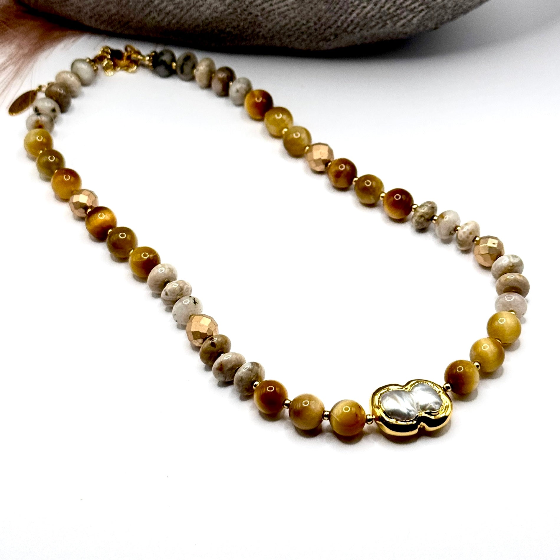 Full view of beaded necklace with gold tiger eye and jasper beads with focus on pearl centerpiece.