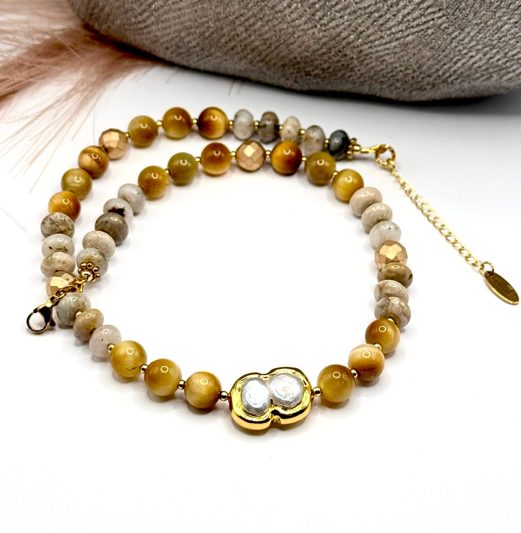Full front view of beaded necklace with gold tiger eye and jasper beads with focus on pearl centerpiece.