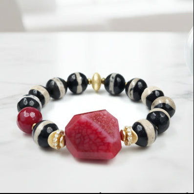 Bracelet with red, black, and gold beads on a white background